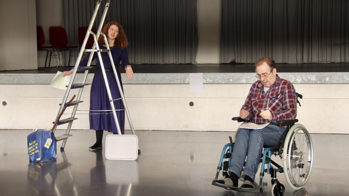 A young woman with a ladder talking to a man in a wheel chair